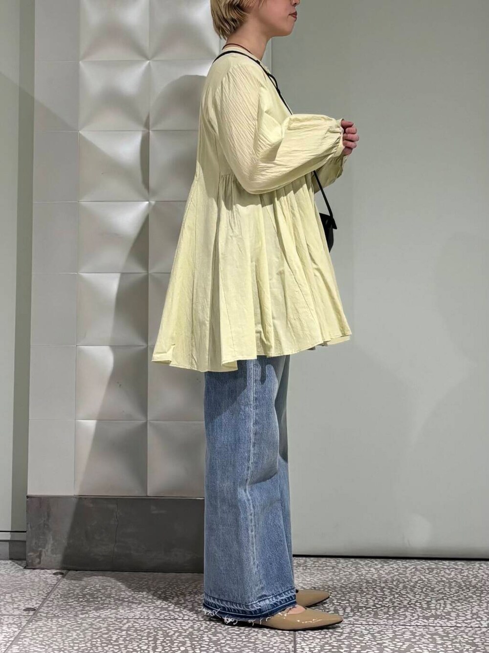 ブルー系のデニムパンツ、ベージュ系のパンプス、グリーン系のシャツ/ブラウスを着用したレディースの春コーディネートの2枚目の写真