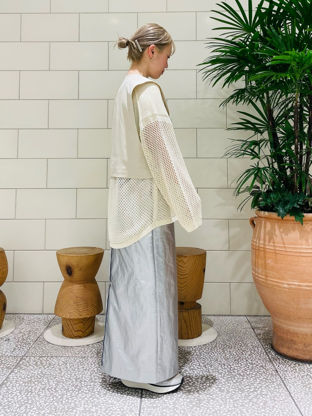 ホワイト系のベスト、ホワイト系のニット/セーター、シルバー系のスカートを着用したレディースの冬コーディネートの2枚目の写真