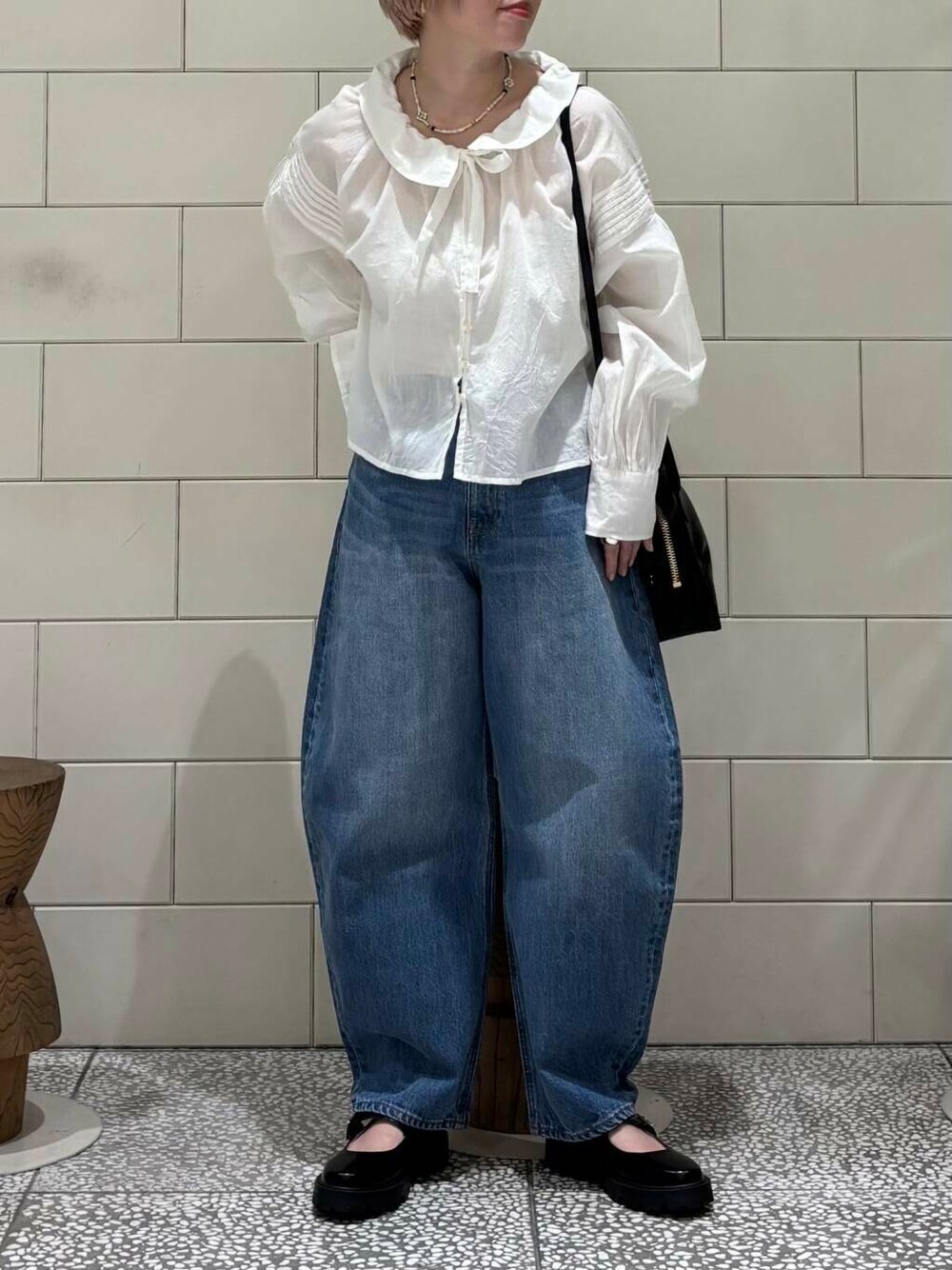 ブルー系のデニムパンツ、ブラック系のショルダーバッグ、ホワイト系のシャツ/ブラウスを着用したレディースの春コーディネートの2枚目の写真