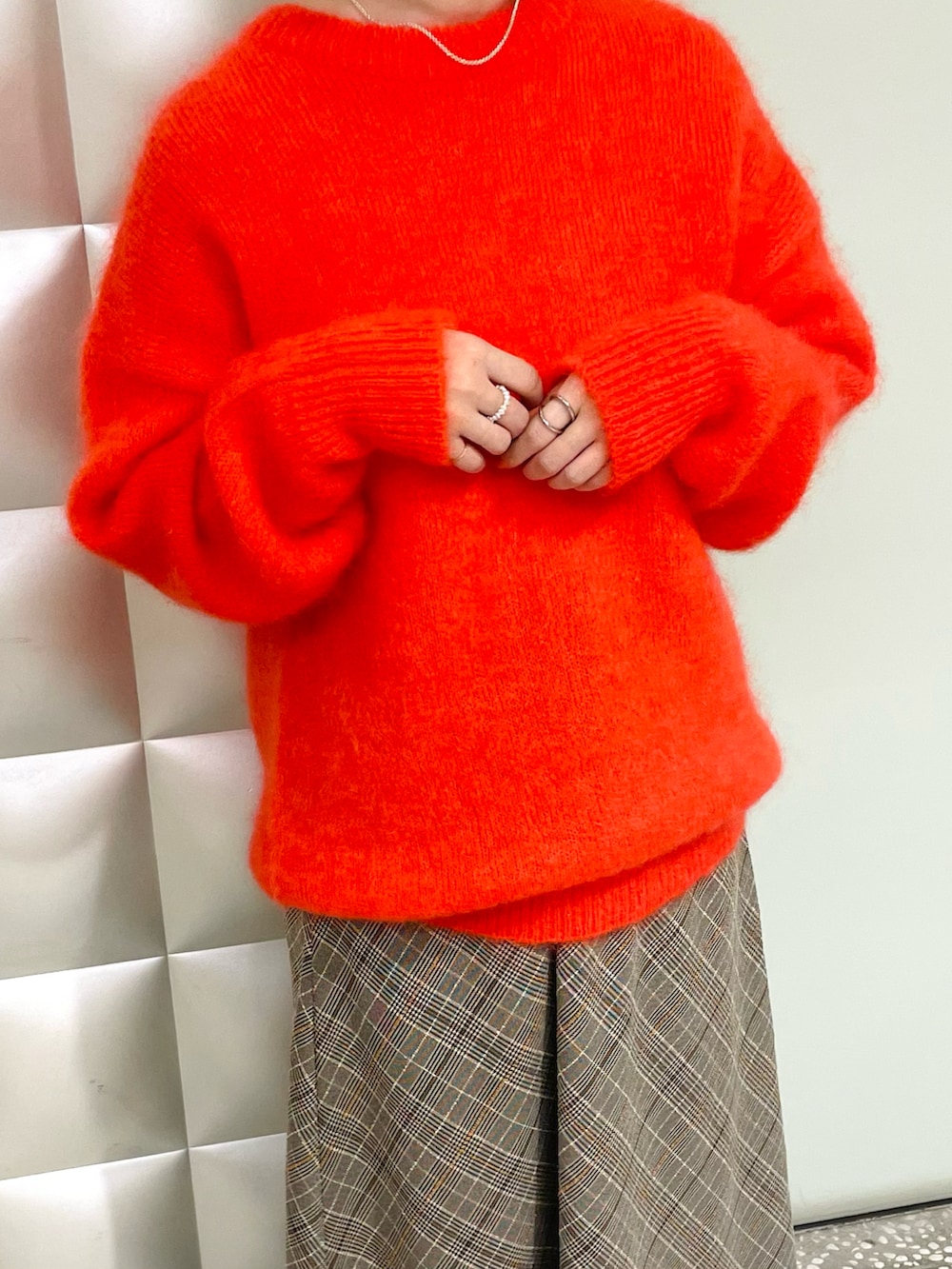 オレンジ系のニット/セーター、ベージュ系のスカート、ベージュ系のブーツを着用したレディースの秋コーディネートの3枚目の写真