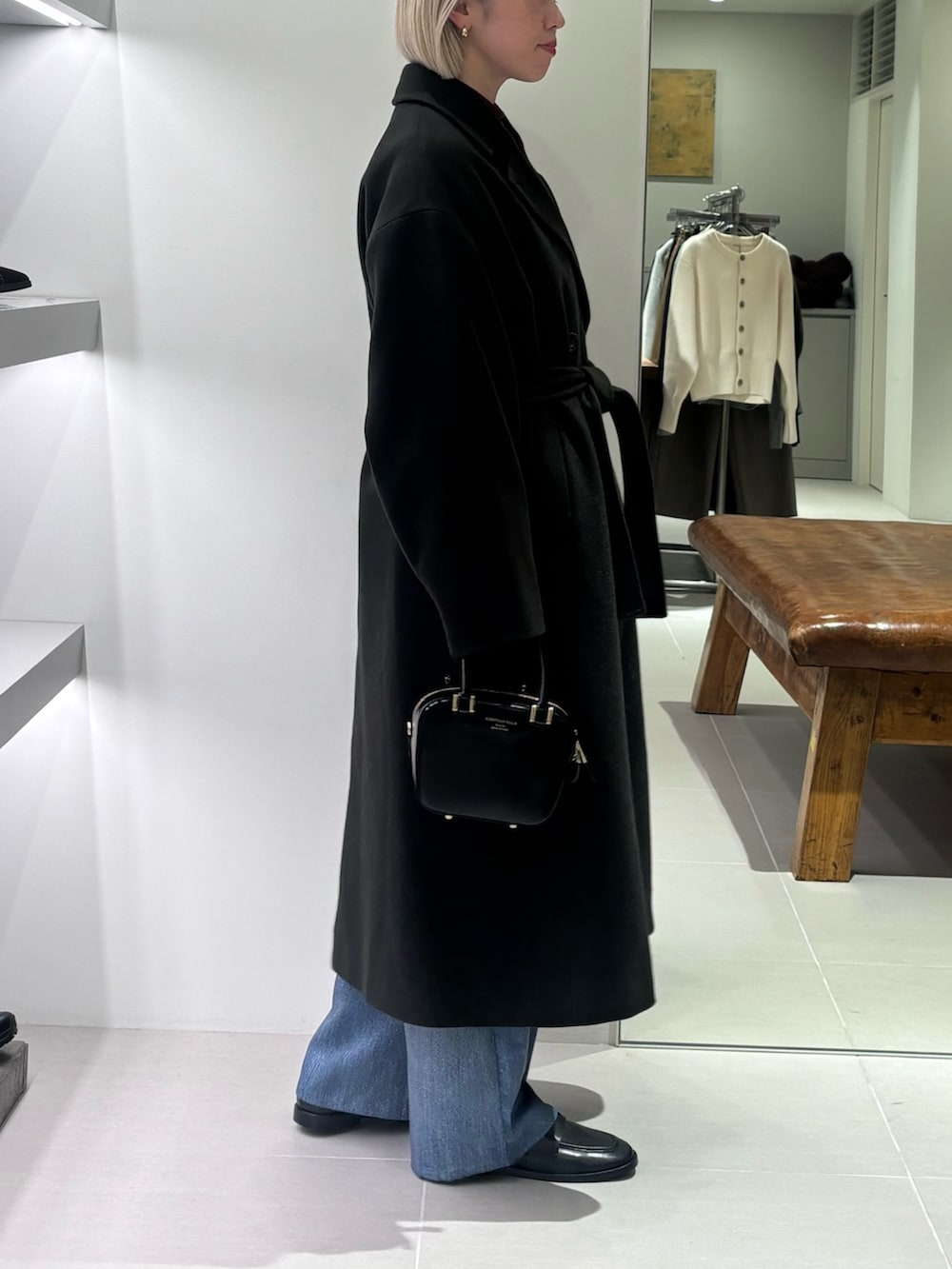 グリーン系のチェスターコート、ブルー系のその他パンツ、ブラック系のショルダーバッグを着用したレディースの秋コーディネートの2枚目の写真