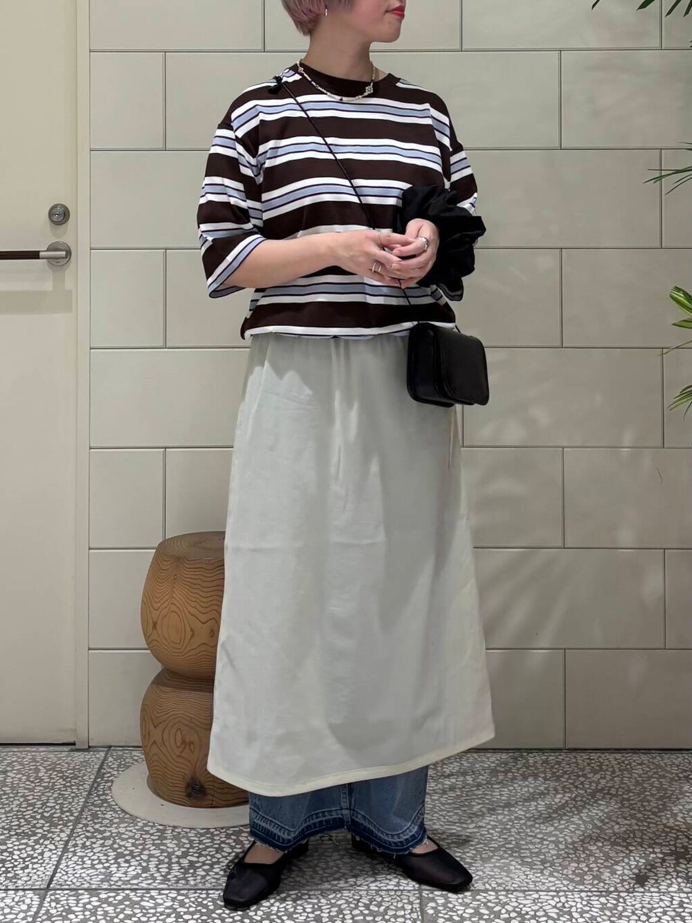 ブルー系のデニムパンツ、ブラック系のショルダーバッグ、ブラック系のパンプスを着用したレディースの春コーディネートの3枚目の写真