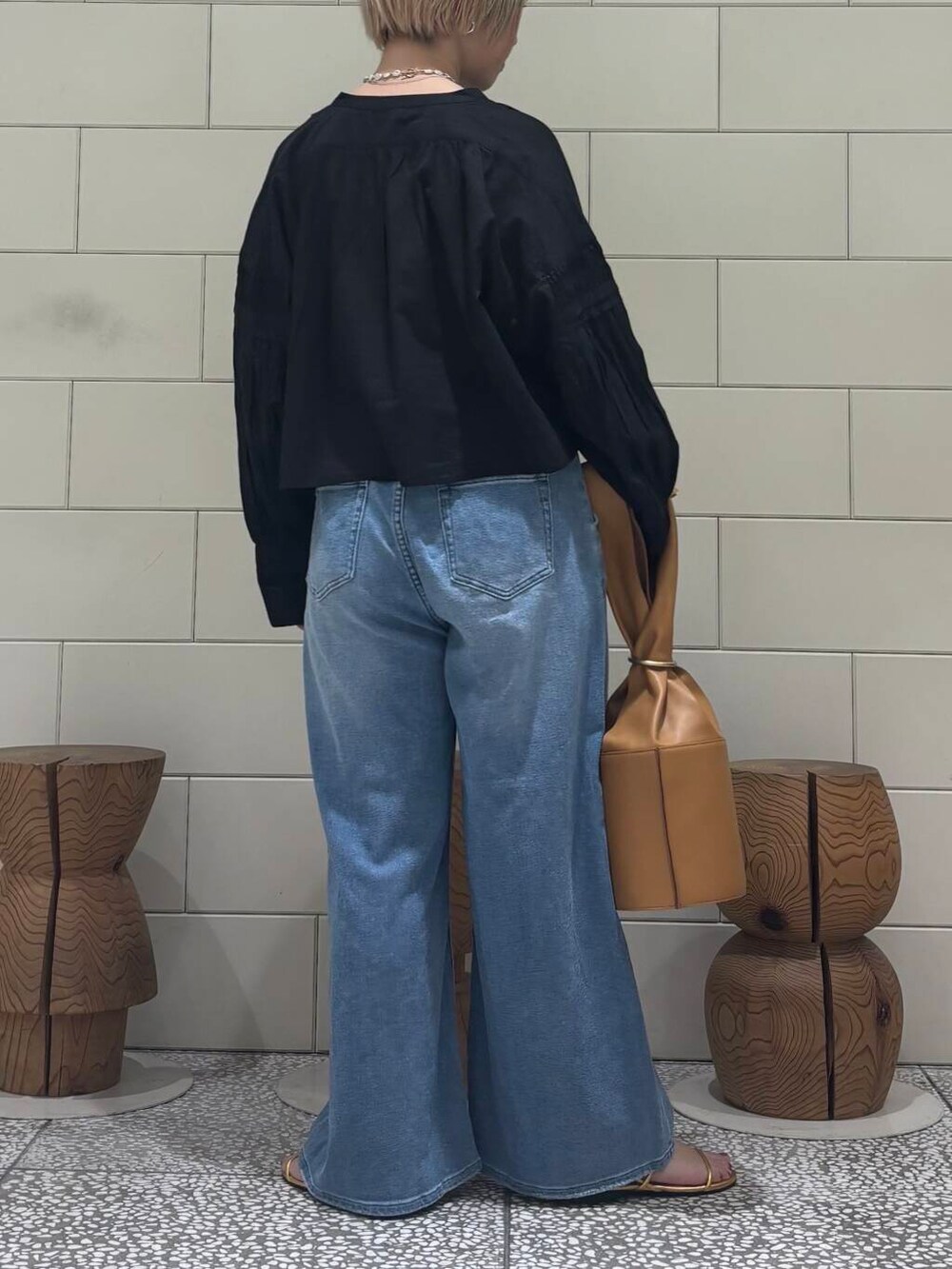 ブラック系のシャツ/ブラウス、ブルー系のデニムパンツ、ゴールド系のサンダルを着用したレディースの春コーディネートの4枚目の写真