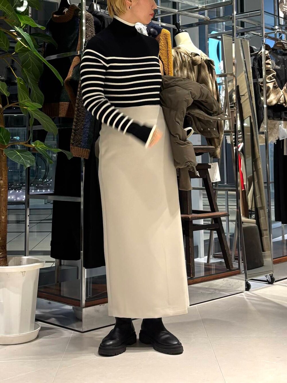 グリーン系のダウンジャケット/コート、ブラック系のニット/セーター、ベージュ系のスカートを着用したレディースの秋コーディネートの4枚目の写真