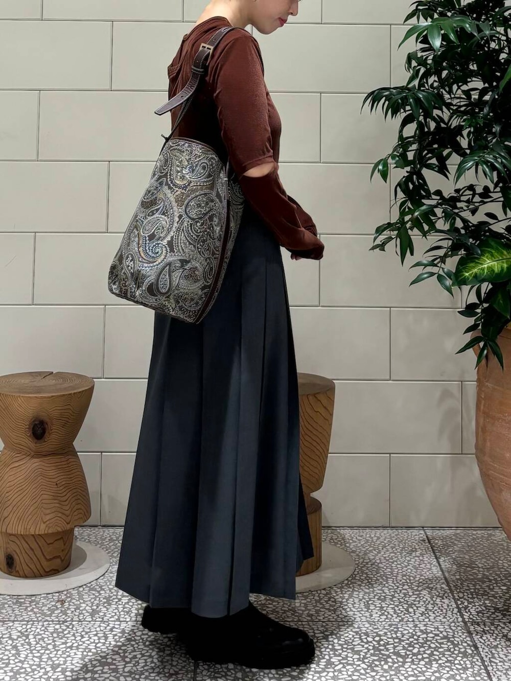 グレー系のスカート、ブラウン系のTシャツ/カットソー、ブラック系のブーツを着用したレディースの秋コーディネートの2枚目の写真