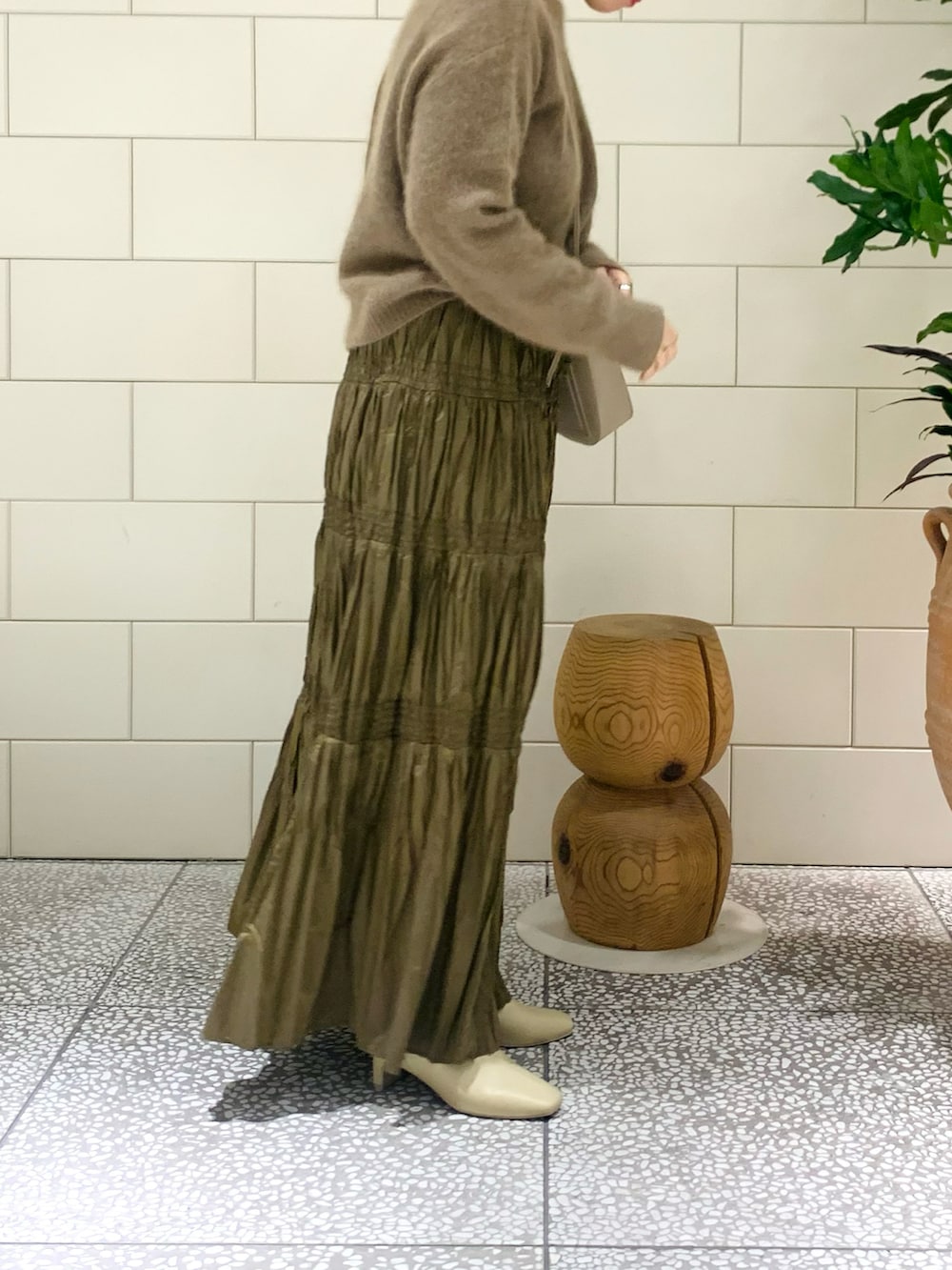 イエロー系のカーディガン/ボレロ、ブラウン系のスカート、ベージュ系のショルダーバッグを着用したレディースの冬コーディネートの2枚目の写真