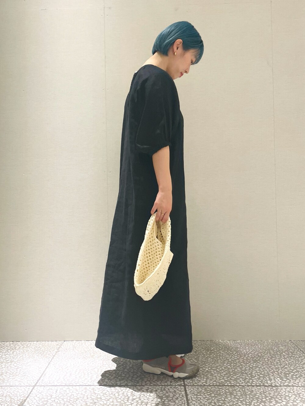 ブラック系のワンピース、ホワイト系のショルダーバッグ、グレー系のスニーカーを着用したレディースの春コーディネートの2枚目の写真