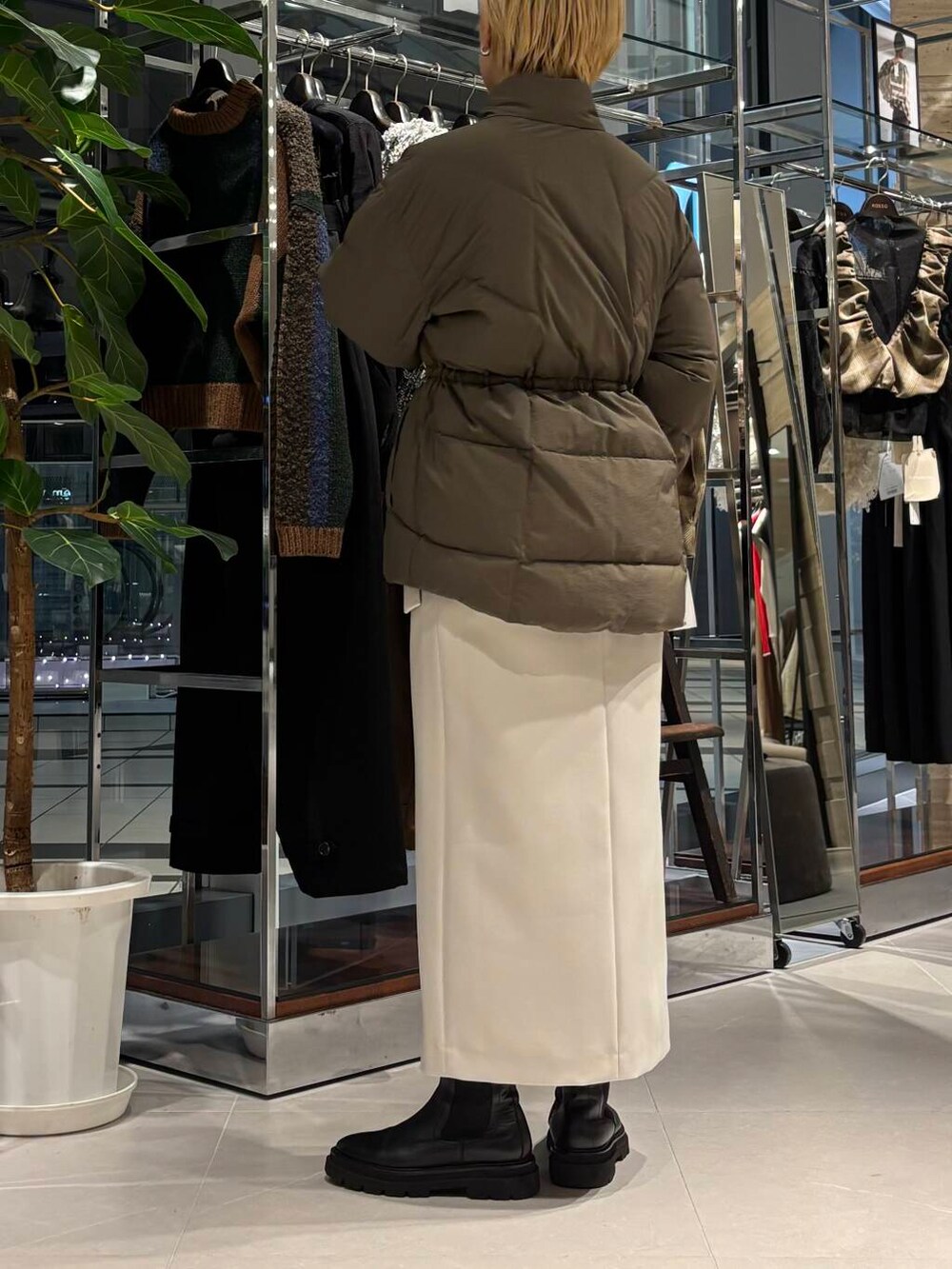 グリーン系のダウンジャケット/コート、ブラック系のニット/セーター、ベージュ系のスカートを着用したレディースの秋コーディネートの3枚目の写真