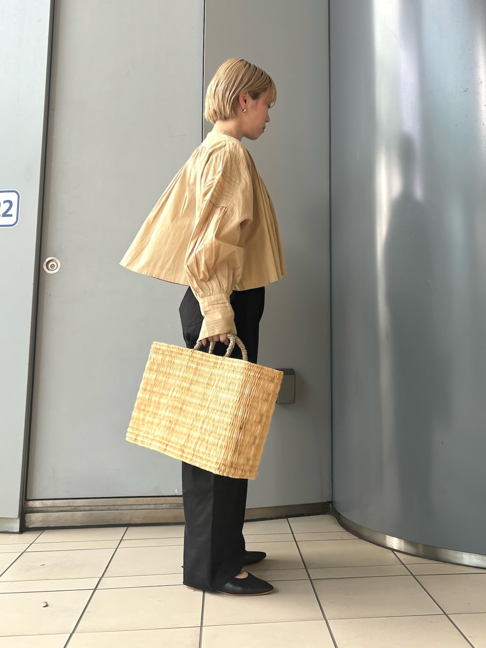 ベージュ系のシャツ/ブラウス、ブラック系のチノパンツ、ベージュ系のハンドバッグを着用したレディースの春コーディネートの2枚目の写真