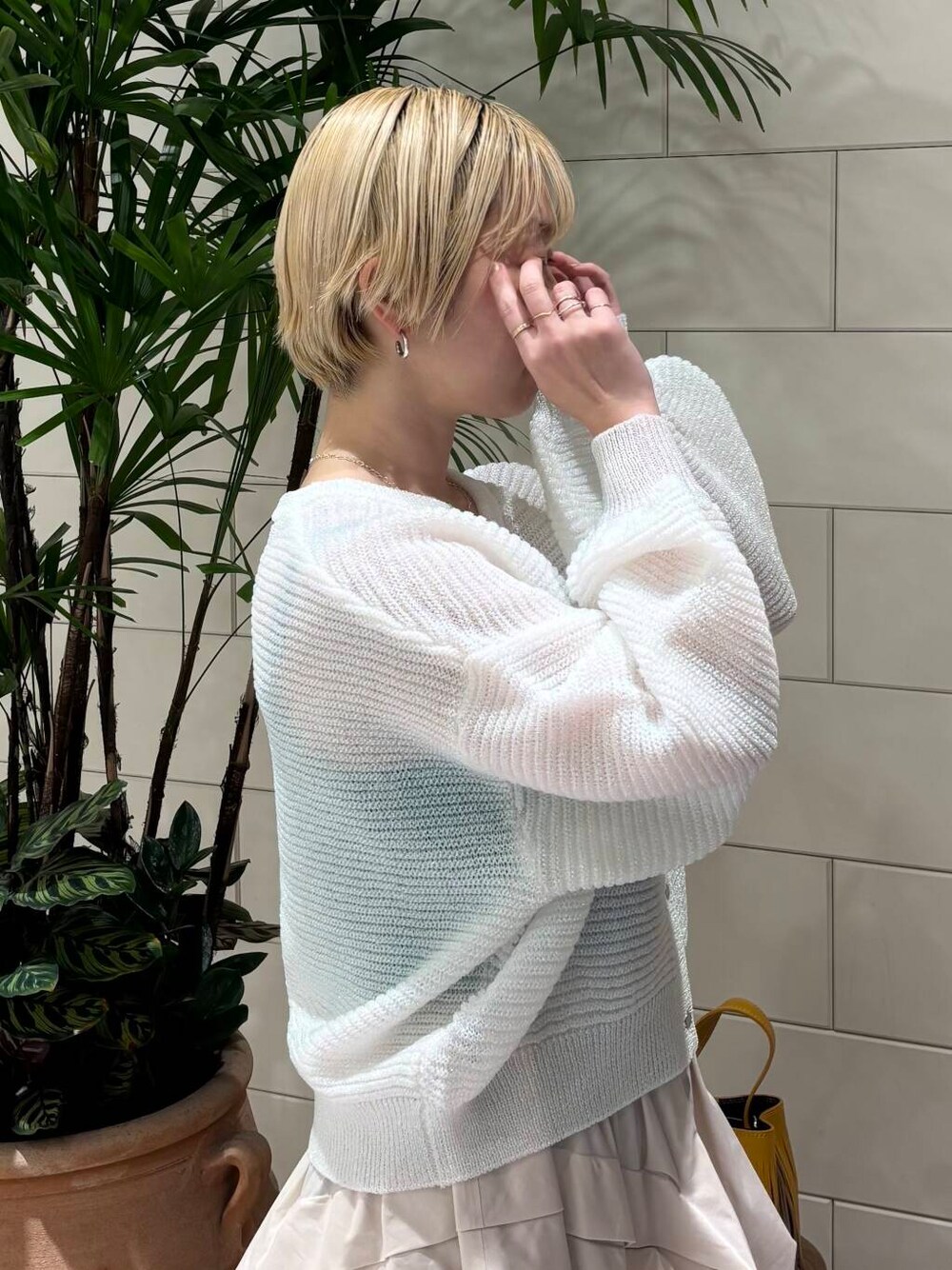 ホワイト系のスカート、ホワイト系のカーディガン/ボレロ、イエロー系のハンドバッグを着用したレディースの冬コーディネートの4枚目の写真