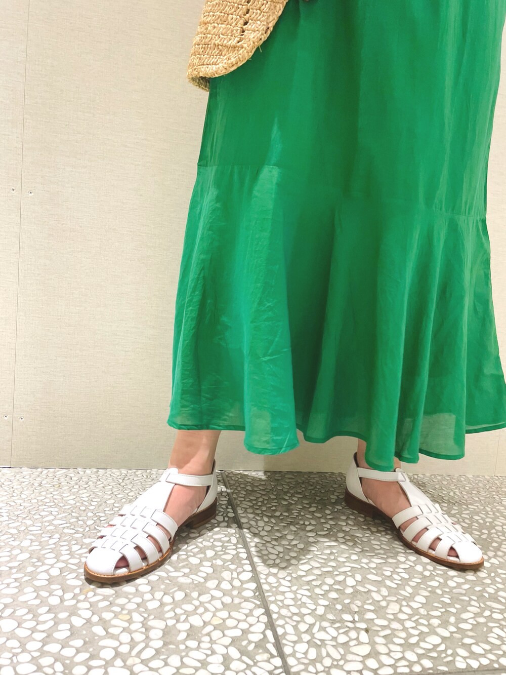 グリーン系のワンピース、ベージュ系のトートバッグ、ホワイト系のサンダルを着用したレディースの春コーディネートの4枚目の写真