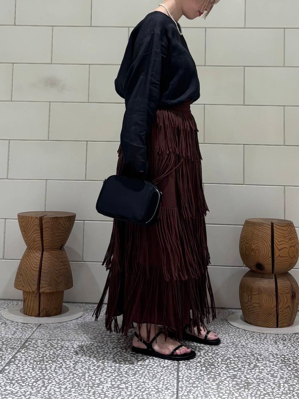 ブラック系のシャツ/ブラウス、ブラック系のボストンバッグ、ブラウン系のスカートを着用したレディースの春コーディネートの2枚目の写真