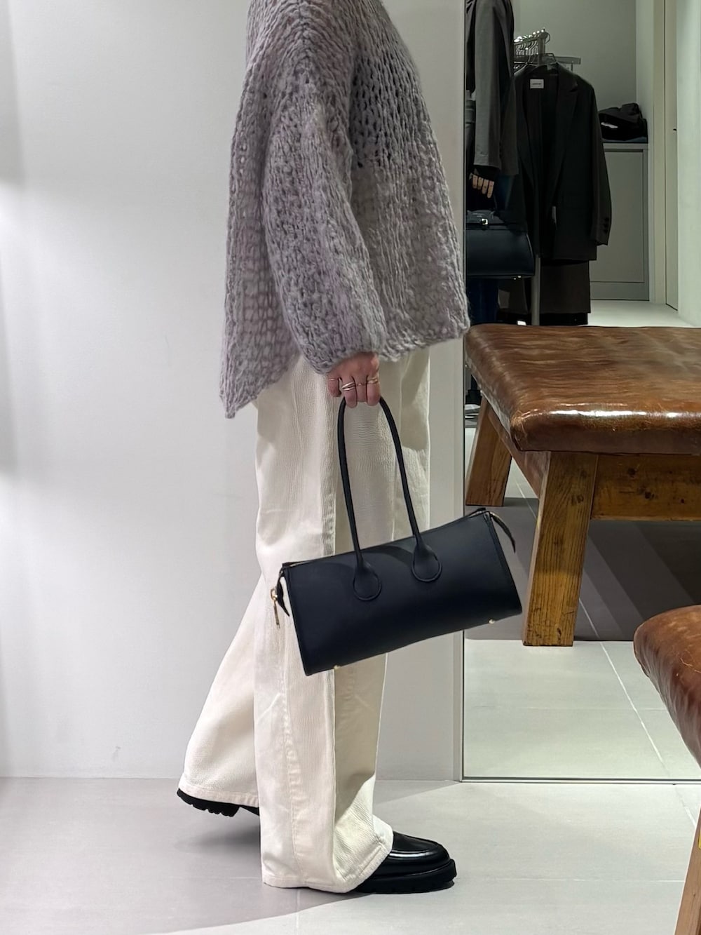 グレー系のニット/セーター、ホワイト系のその他パンツ、ブラック系のショルダーバッグを着用したレディースの秋コーディネートの3枚目の写真