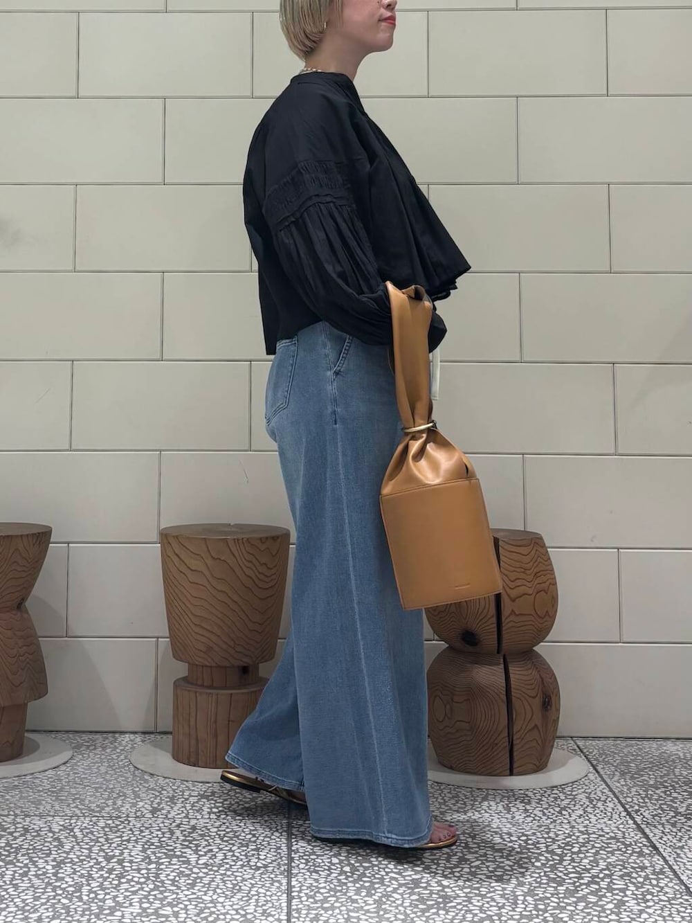 ブラック系のシャツ/ブラウス、ブルー系のデニムパンツ、ゴールド系のサンダルを着用したレディースの春コーディネートの3枚目の写真