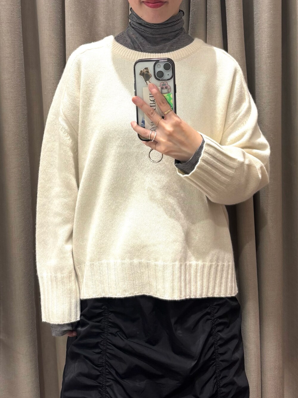 ブラック系のスカート、ホワイト系のニット/セーター、ブラック系のTシャツ/カットソーを着用したレディースの冬コーディネートの3枚目の写真