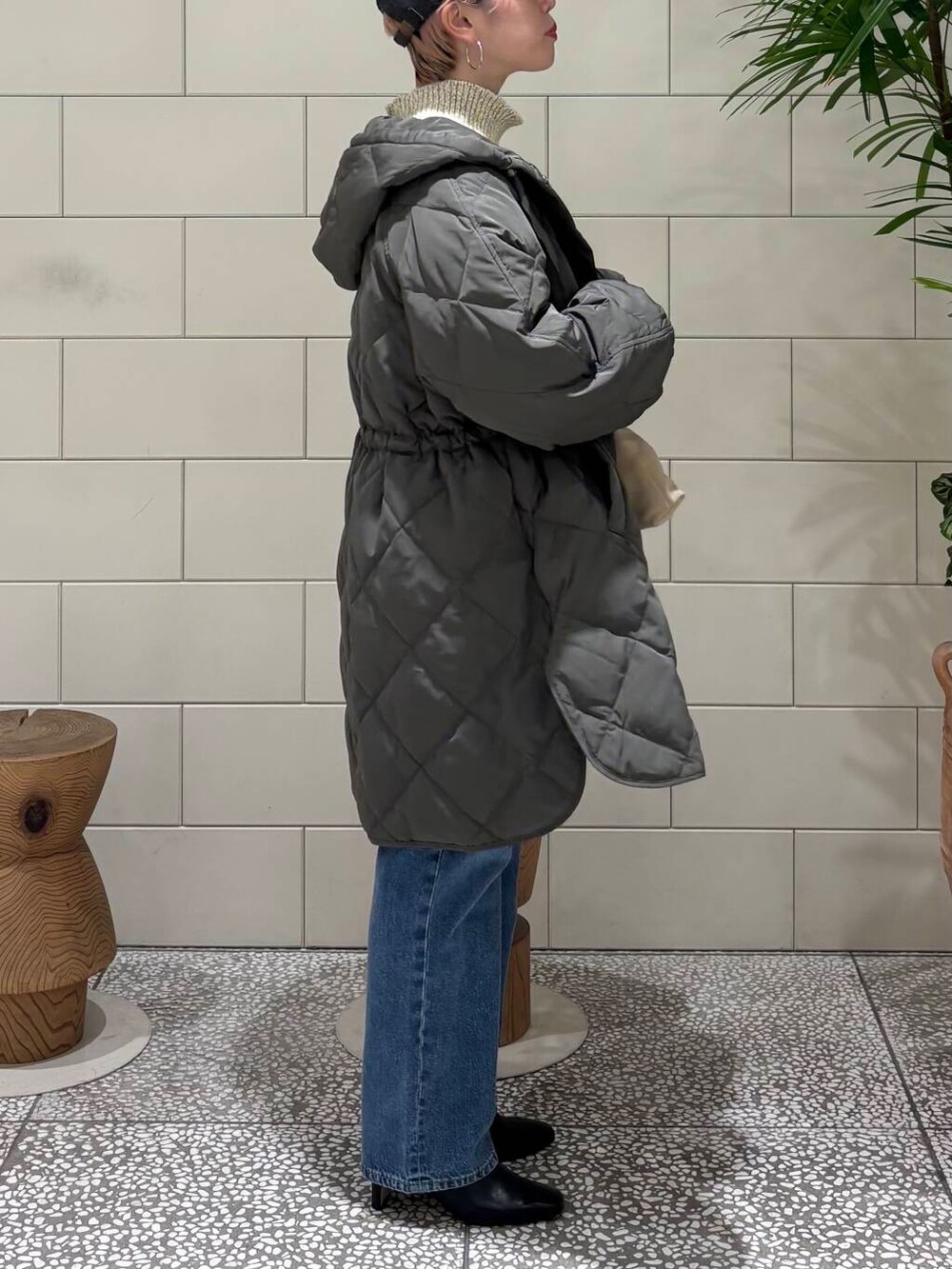 ブルー系のデニムパンツ、ベージュ系のショルダーバッグ、ホワイト系のニット/セーターを着用したレディースの冬コーディネートの3枚目の写真