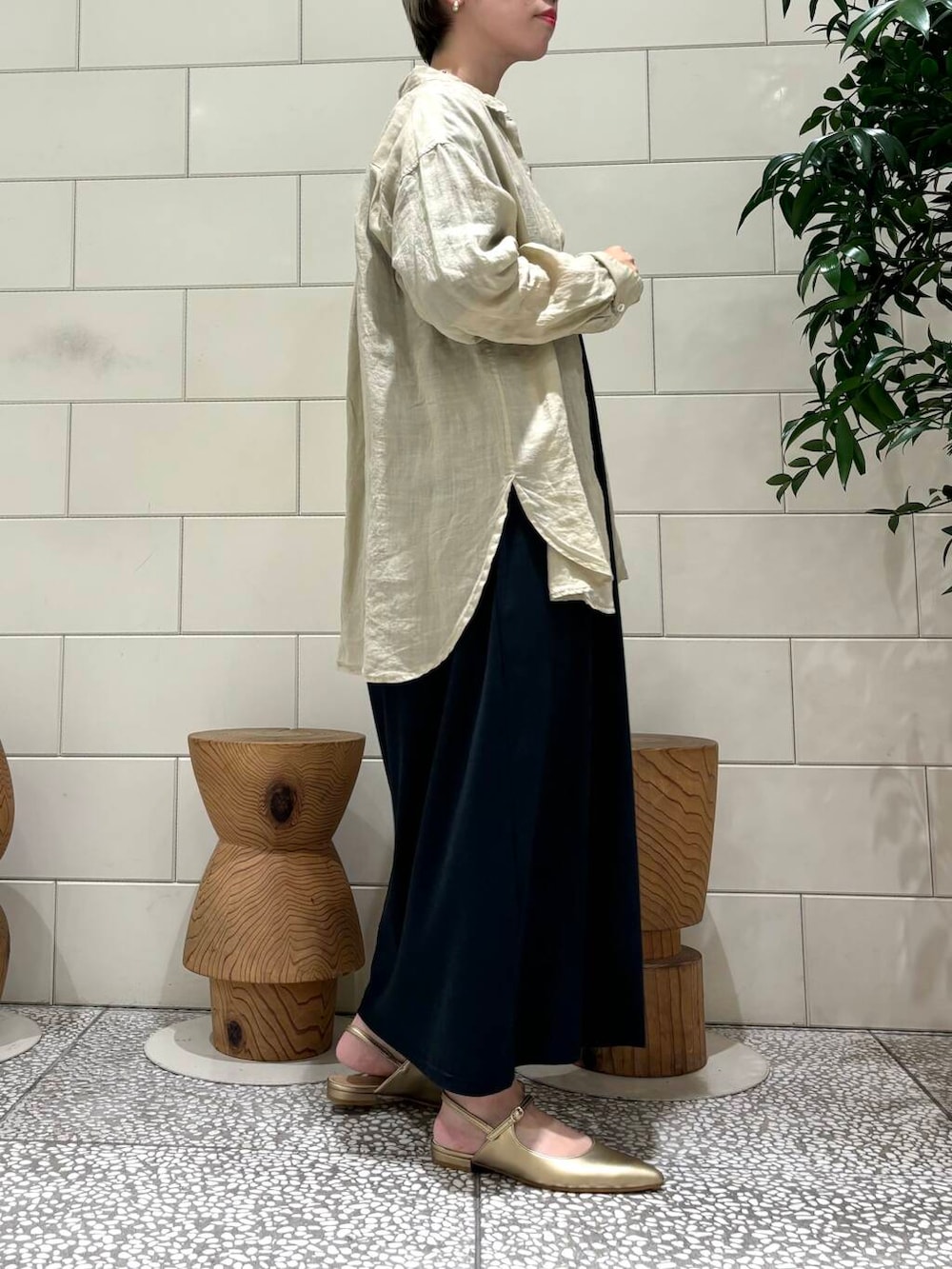 ゴールド系のパンプス、ブラック系のワンピース、ベージュ系のTシャツ/カットソーを着用したレディースの夏コーディネートの2枚目の写真