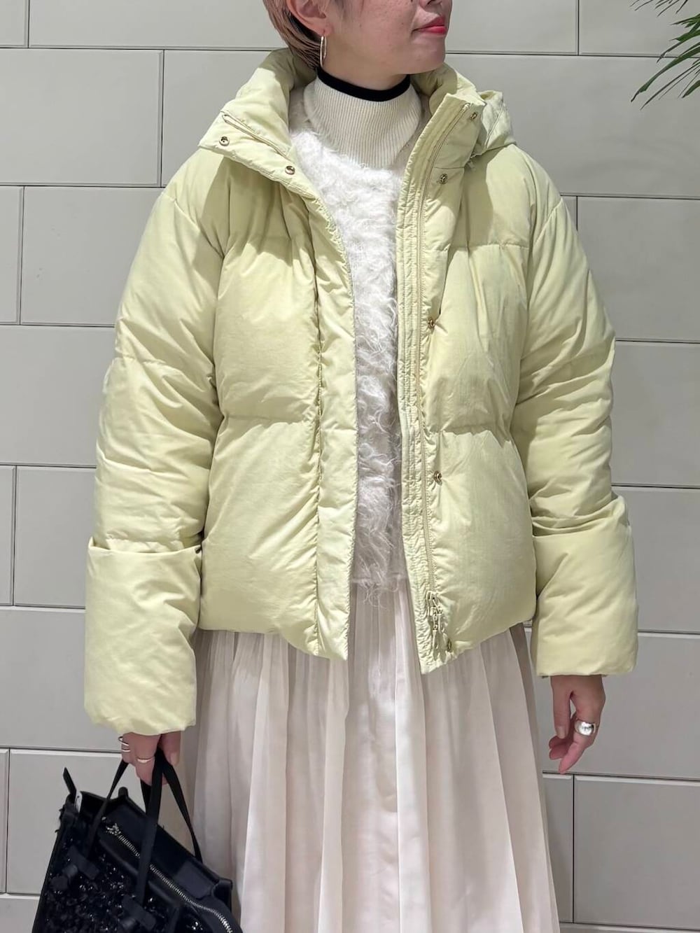 ホワイト系のニット/セーター、ホワイト系のスカート、イエロー系のダウンジャケット/コートを着用したレディースの冬コーディネートの5枚目の写真