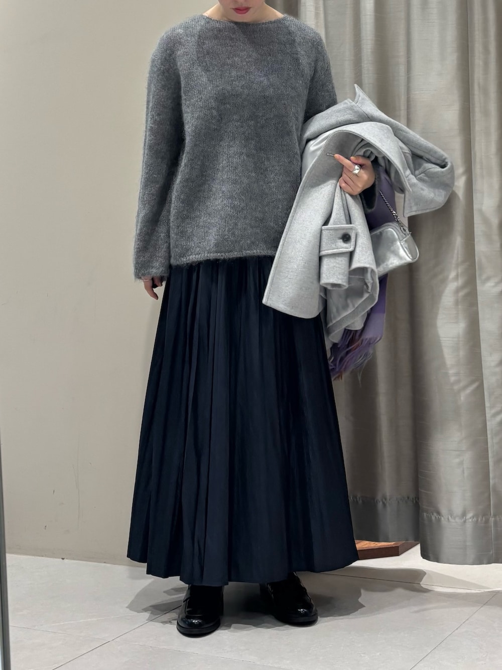 グレー系のニット/セーター、グレー系のピーコート、ブルー系のスカートを着用したレディースの冬コーディネートの2枚目の写真
