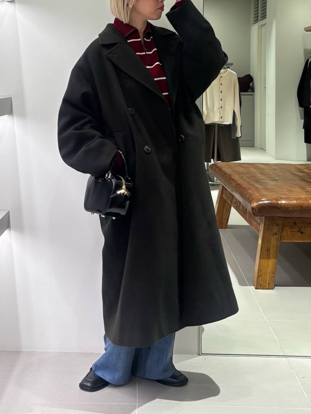 グリーン系のチェスターコート、ブルー系のその他パンツ、ブラック系のショルダーバッグを着用したレディースの秋コーディネートの4枚目の写真