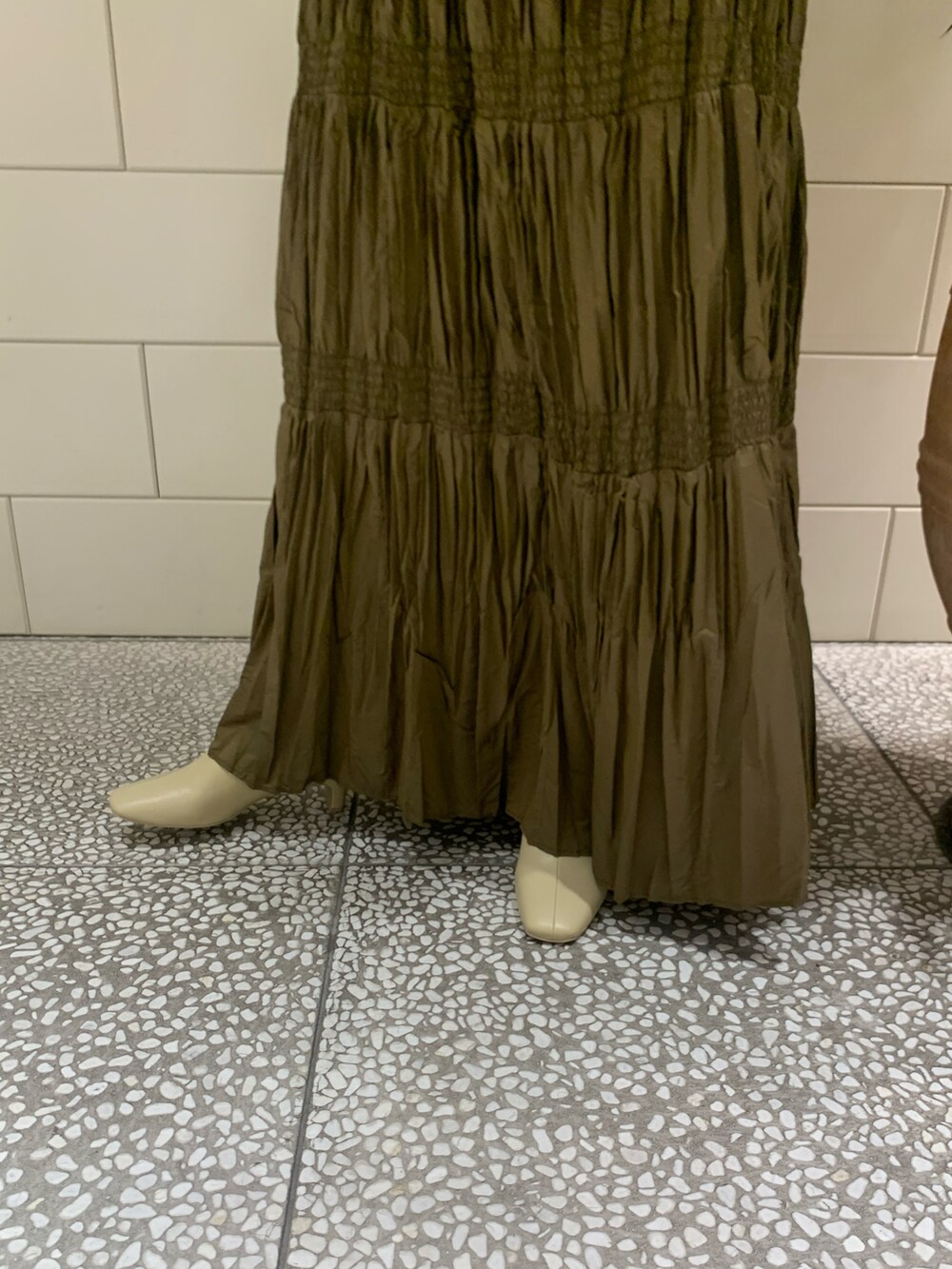 イエロー系のカーディガン/ボレロ、ブラウン系のスカート、ベージュ系のショルダーバッグを着用したレディースの冬コーディネートの4枚目の写真