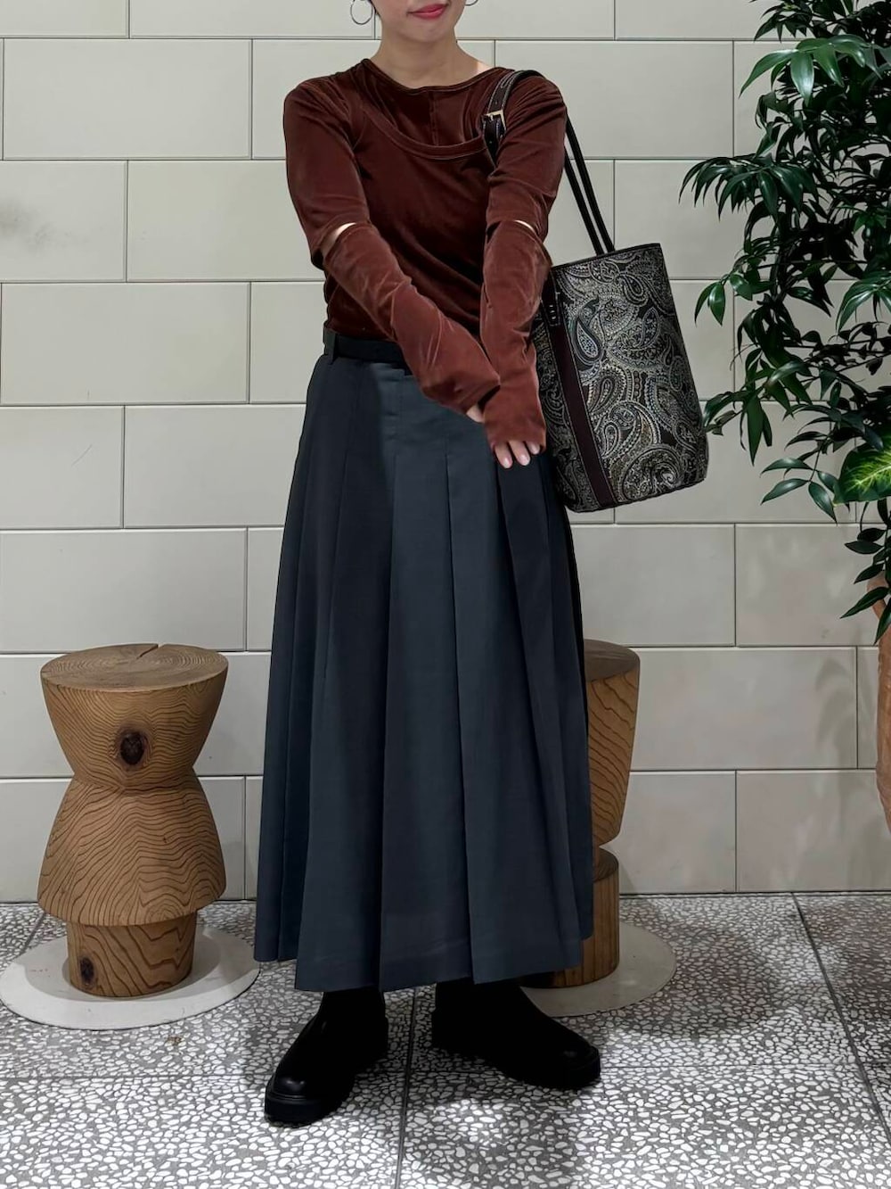 グレー系のスカート、ブラウン系のTシャツ/カットソー、ブラック系のブーツを着用したレディースの秋コーディネートの3枚目の写真