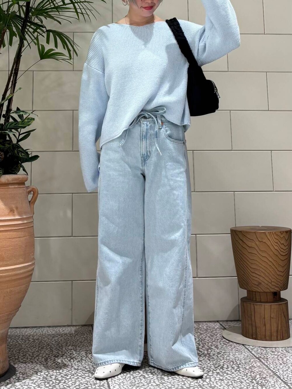 ブラック系のショルダーバッグ、ホワイト系のパンプス、ブルー系のニット/セーターを着用したレディースの春コーディネートの2枚目の写真