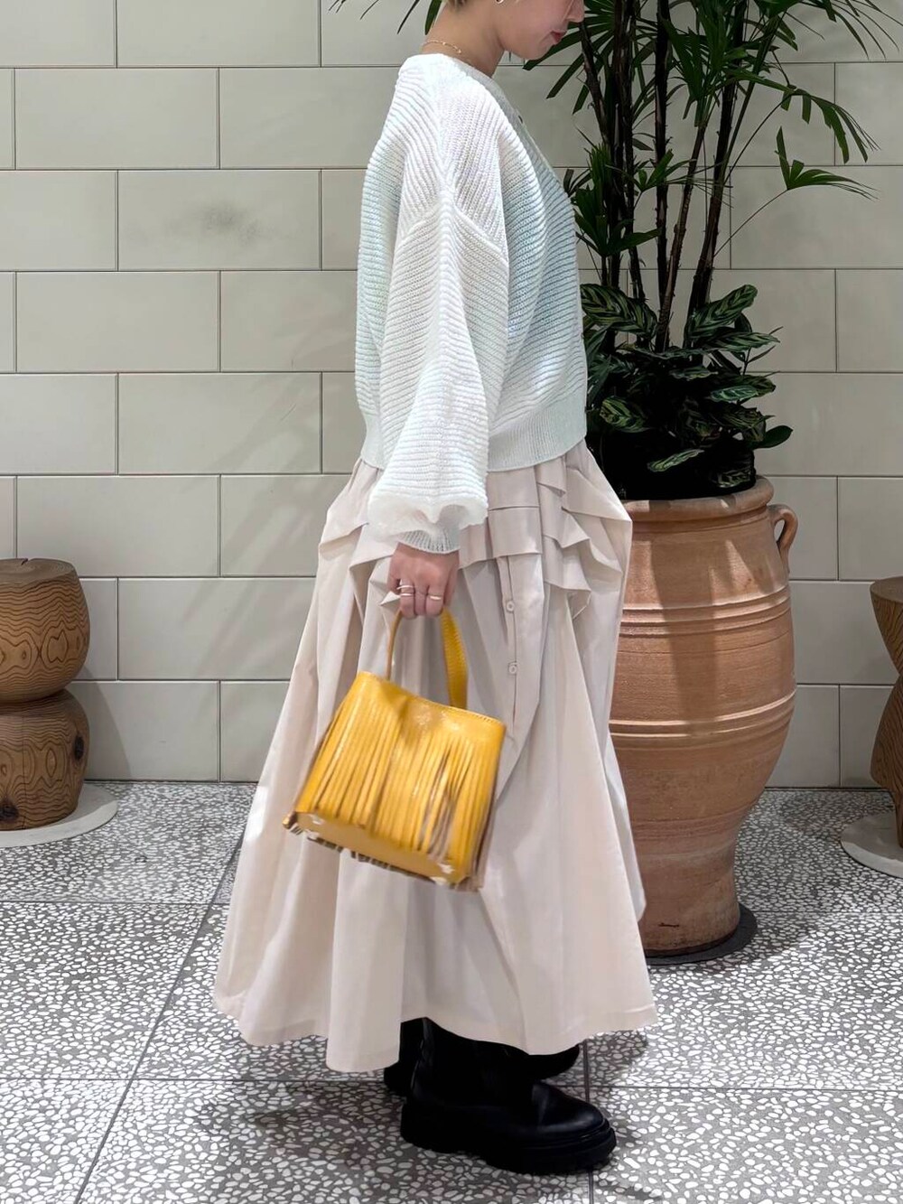 ホワイト系のスカート、ホワイト系のカーディガン/ボレロ、イエロー系のハンドバッグを着用したレディースの冬コーディネートの2枚目の写真