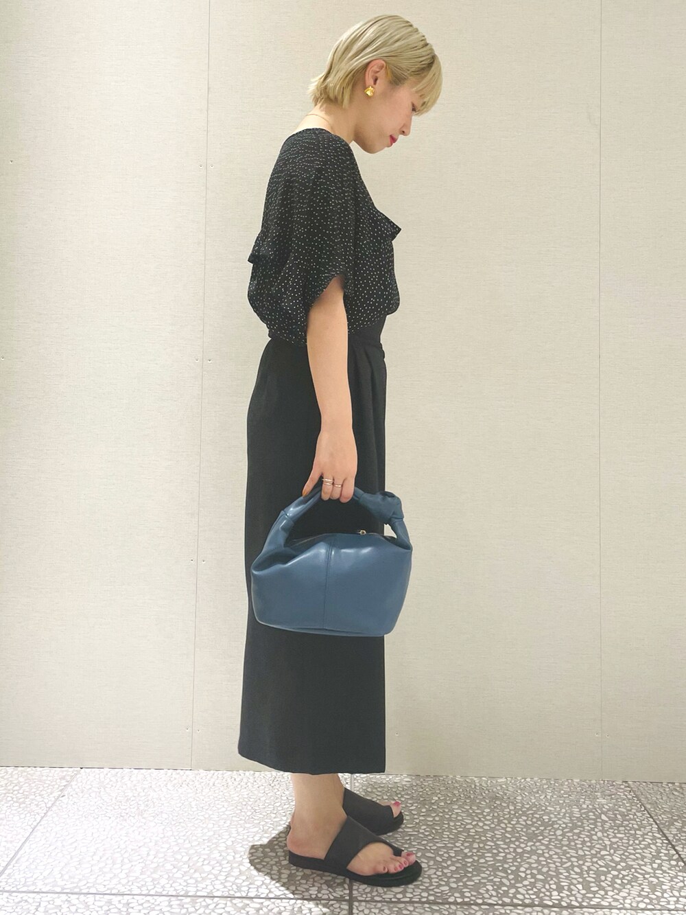 ブラック系のシャツ/ブラウス、ブラック系のスカート、ブルー系のハンドバッグを着用したレディースの春コーディネートの2枚目の写真