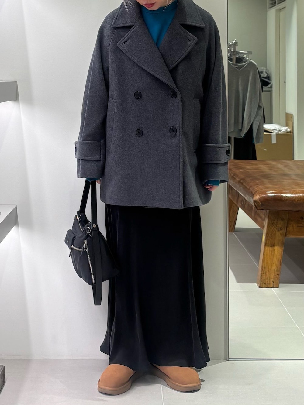 グレー系のピーコート、ブルー系のニット/セーター、ブラック系のショルダーバッグを着用したレディースの秋コーディネートの2枚目の写真