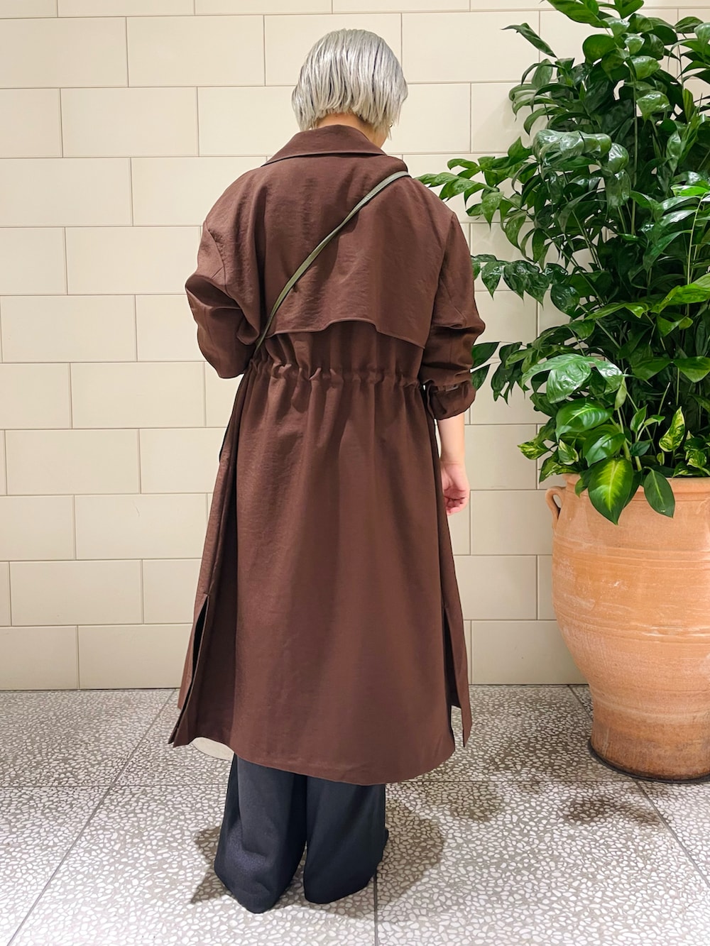 ブラウン系のトレンチコート、ホワイト系のシャツ/ブラウス、グリーン系のショルダーバッグを着用したレディースの秋コーディネートの3枚目の写真