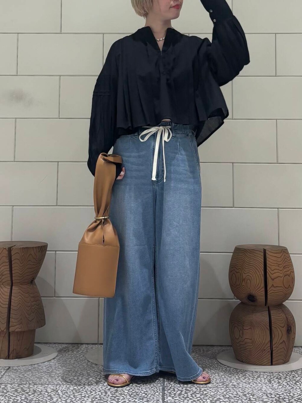 ブラック系のシャツ/ブラウス、ブルー系のデニムパンツ、ゴールド系のサンダルを着用したレディースの春コーディネートの2枚目の写真