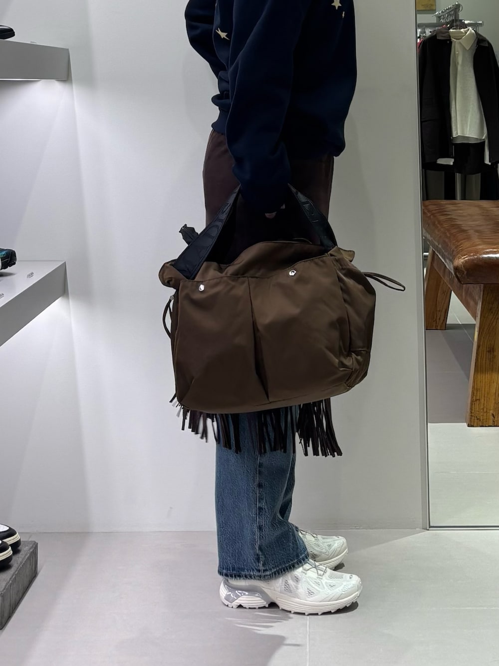 ブラウン系のスカート、ブルー系のデニムパンツ、ブラウン系のショルダーバッグを着用したレディースの秋コーディネートの2枚目の写真