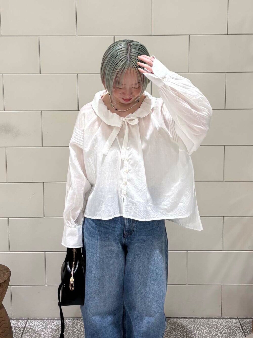 ブルー系のデニムパンツ、ブラック系のショルダーバッグ、ホワイト系のシャツ/ブラウスを着用したレディースの春コーディネートの5枚目の写真