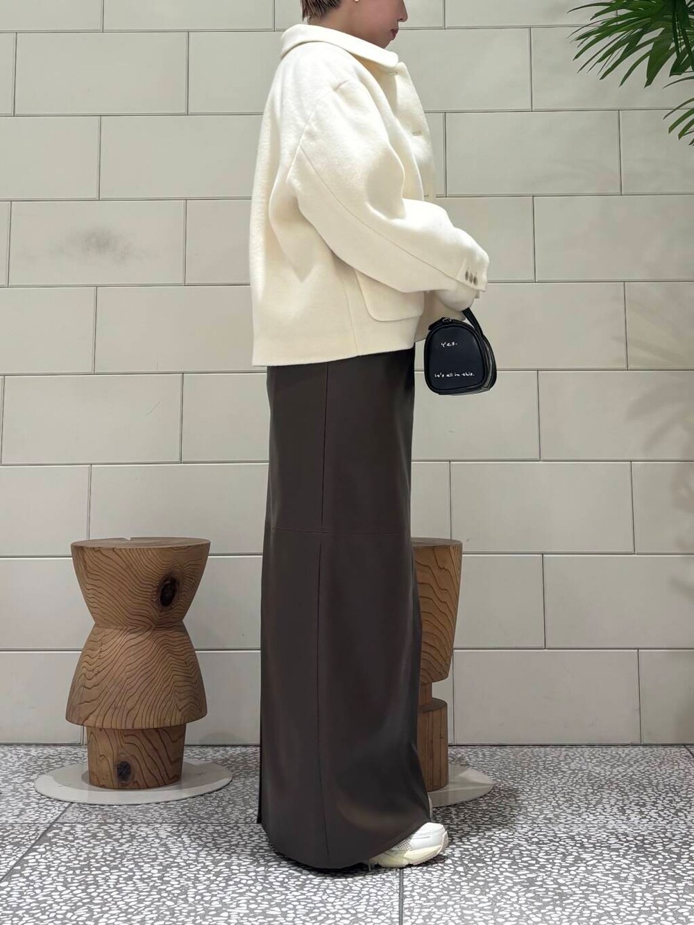 ホワイト系のスニーカー、ブラック系のボストンバッグ、ブラウン系のスカートを着用したレディースの冬コーディネートの3枚目の写真