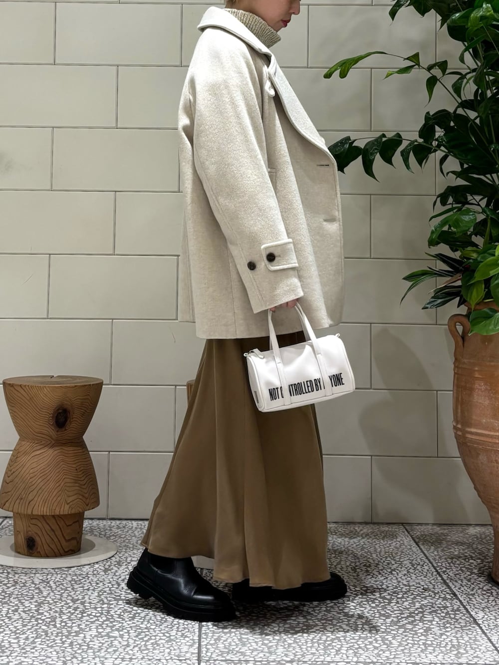 イエロー系のスカート、ホワイト系のボストンバッグ、ホワイト系のニット/セーターを着用したレディースの秋コーディネートの2枚目の写真