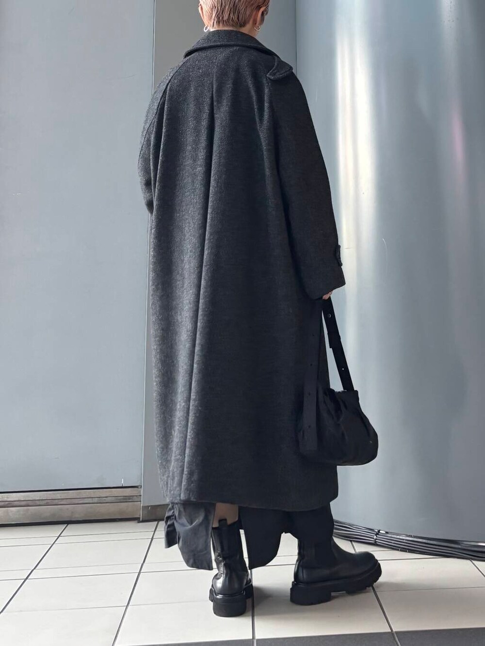 ブラック系のステンカラーコート、ブラック系のスカート、ブラック系のニット/セーターを着用したレディースの冬コーディネートの3枚目の写真