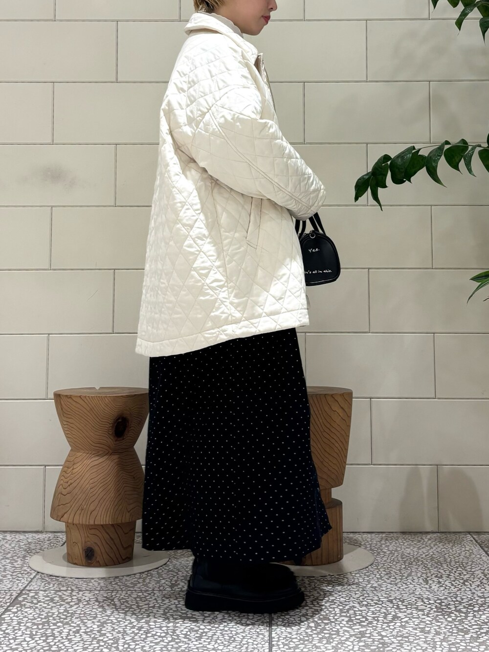 ブラック系のボストンバッグ、ブラック系のワンピース、ホワイト系のダウンジャケット/コートを着用したレディースの秋コーディネートの2枚目の写真