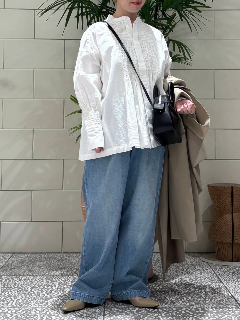ブルー系のデニムパンツ、ベージュ系のトレンチコート、ホワイト系のシャツ/ブラウスを着用したレディースの冬コーディネートの3枚目の写真