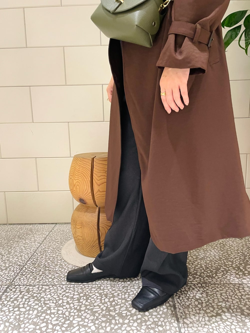 ブラウン系のトレンチコート、ホワイト系のシャツ/ブラウス、グリーン系のショルダーバッグを着用したレディースの秋コーディネートの5枚目の写真