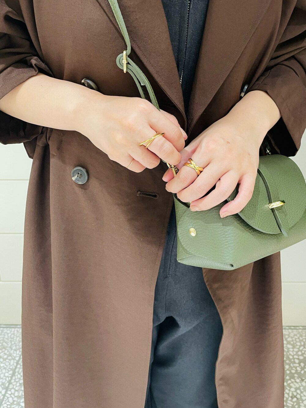 ブラウン系のトレンチコート、ホワイト系のシャツ/ブラウス、グリーン系のショルダーバッグを着用したレディースの秋コーディネートの4枚目の写真