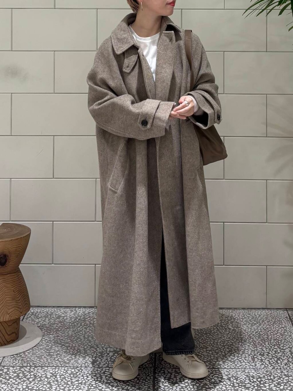 ブラック系のデニムパンツ、ブラウン系のステンカラーコート、ホワイト系のTシャツ/カットソーを着用したレディースの冬コーディネートの4枚目の写真