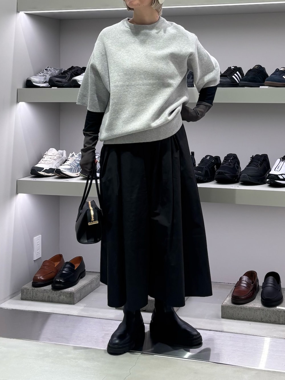 グレー系のニット/セーター、ブラック系のTシャツ/カットソー、ブラック系のショルダーバッグを着用したレディースの秋コーディネートの2枚目の写真
