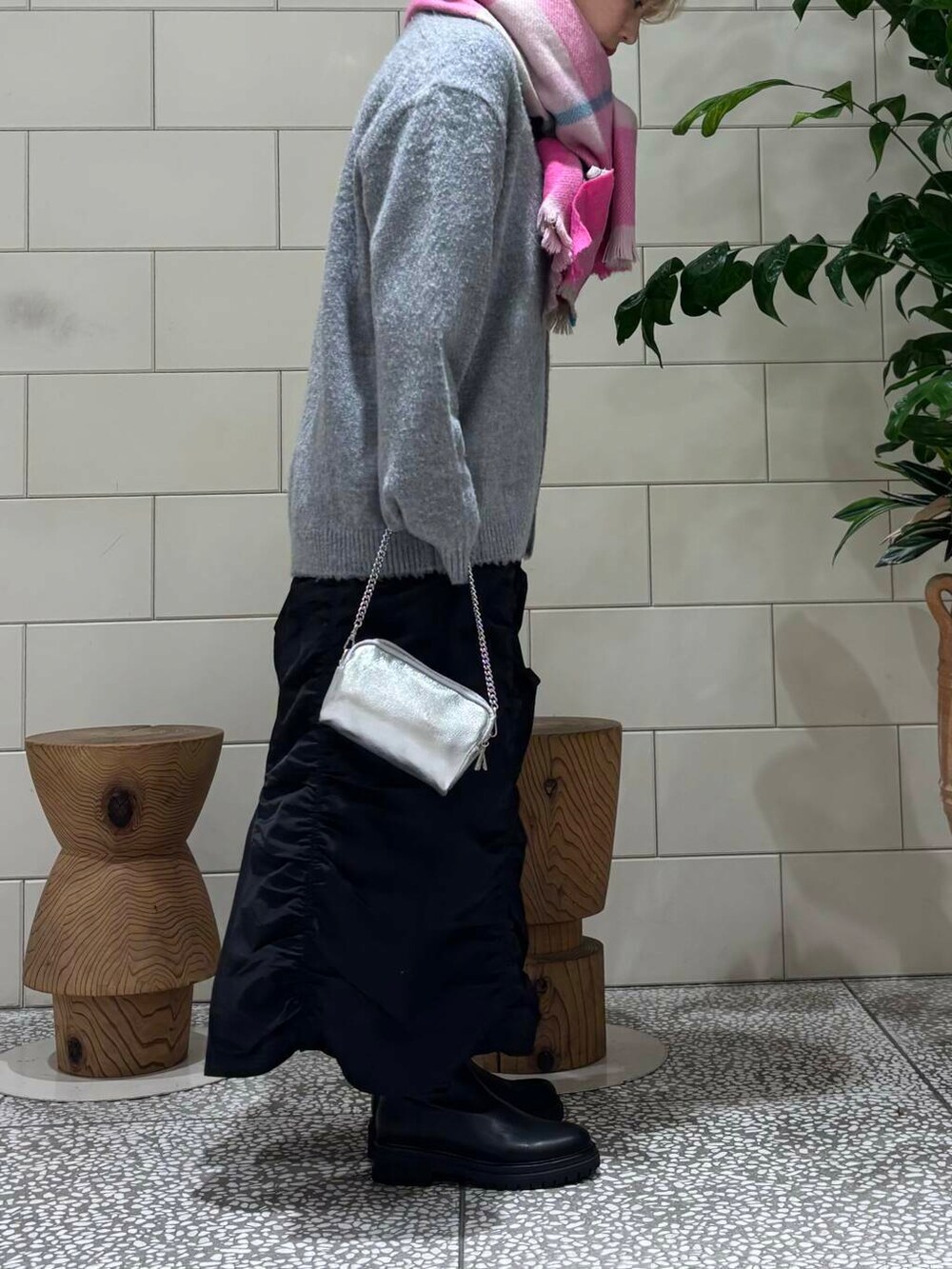 ブラック系のスカート、ブラック系のブーツ、グレー系のカーディガン/ボレロを着用したレディースの秋コーディネートの2枚目の写真