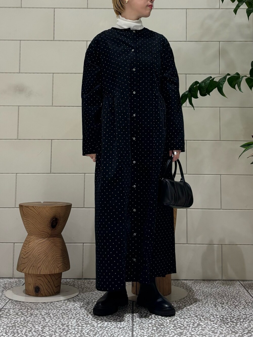 ブラック系のボストンバッグ、ブラック系のワンピース、ホワイト系のダウンジャケット/コートを着用したレディースの秋コーディネートの3枚目の写真