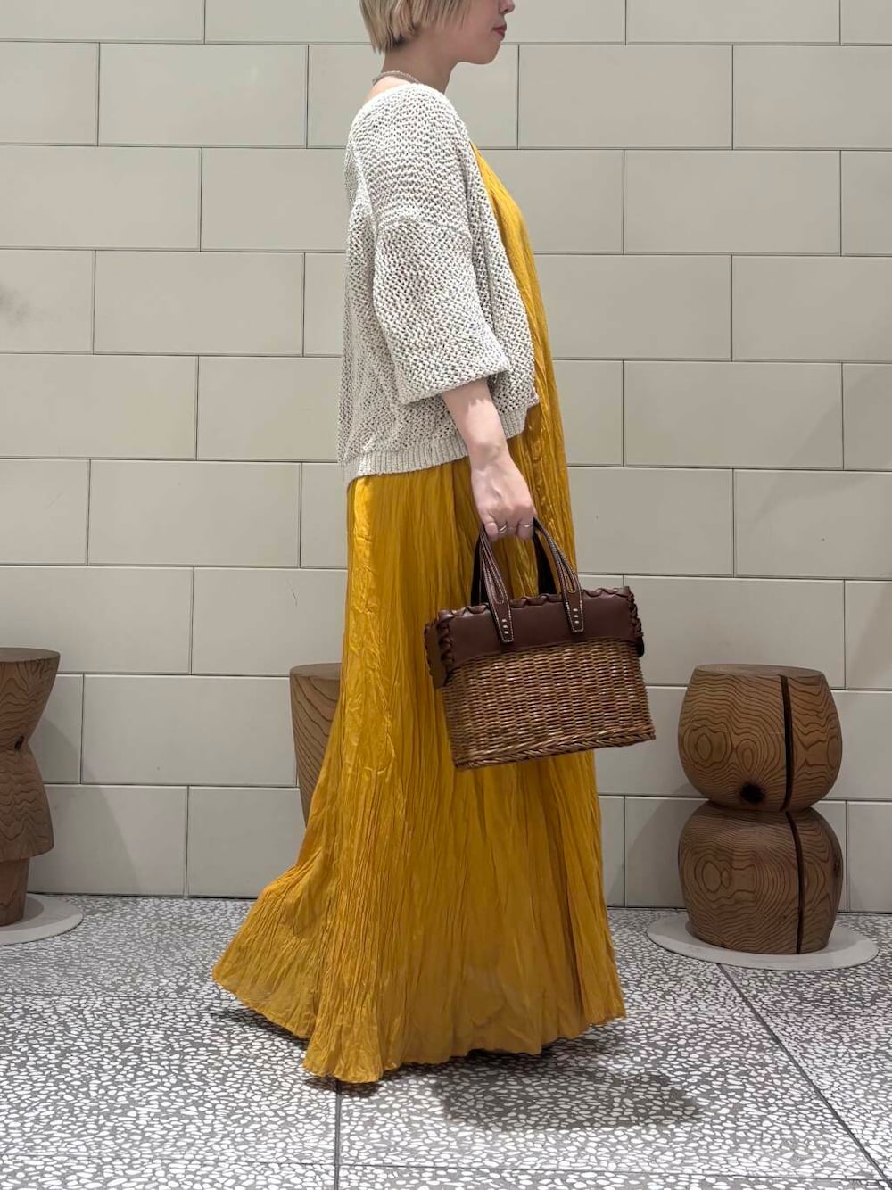 ホワイト系のカーディガン/ボレロ、ベージュ系のサンダル、イエロー系のワンピースを着用したレディースの春コーディネートの2枚目の写真