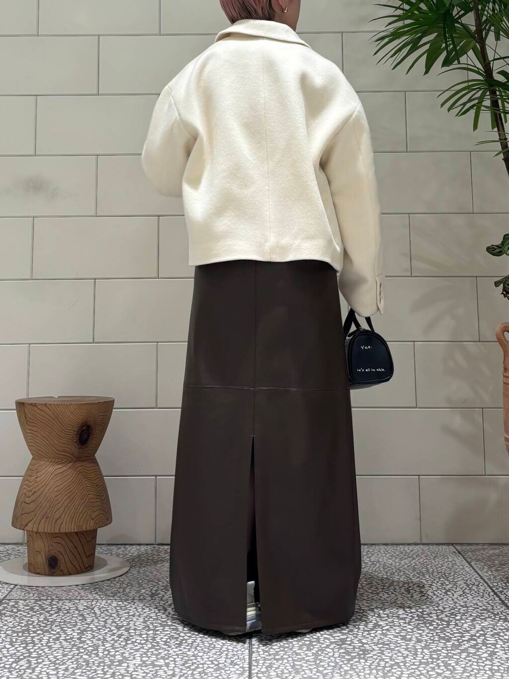 ホワイト系のスニーカー、ブラック系のボストンバッグ、ブラウン系のスカートを着用したレディースの冬コーディネートの4枚目の写真