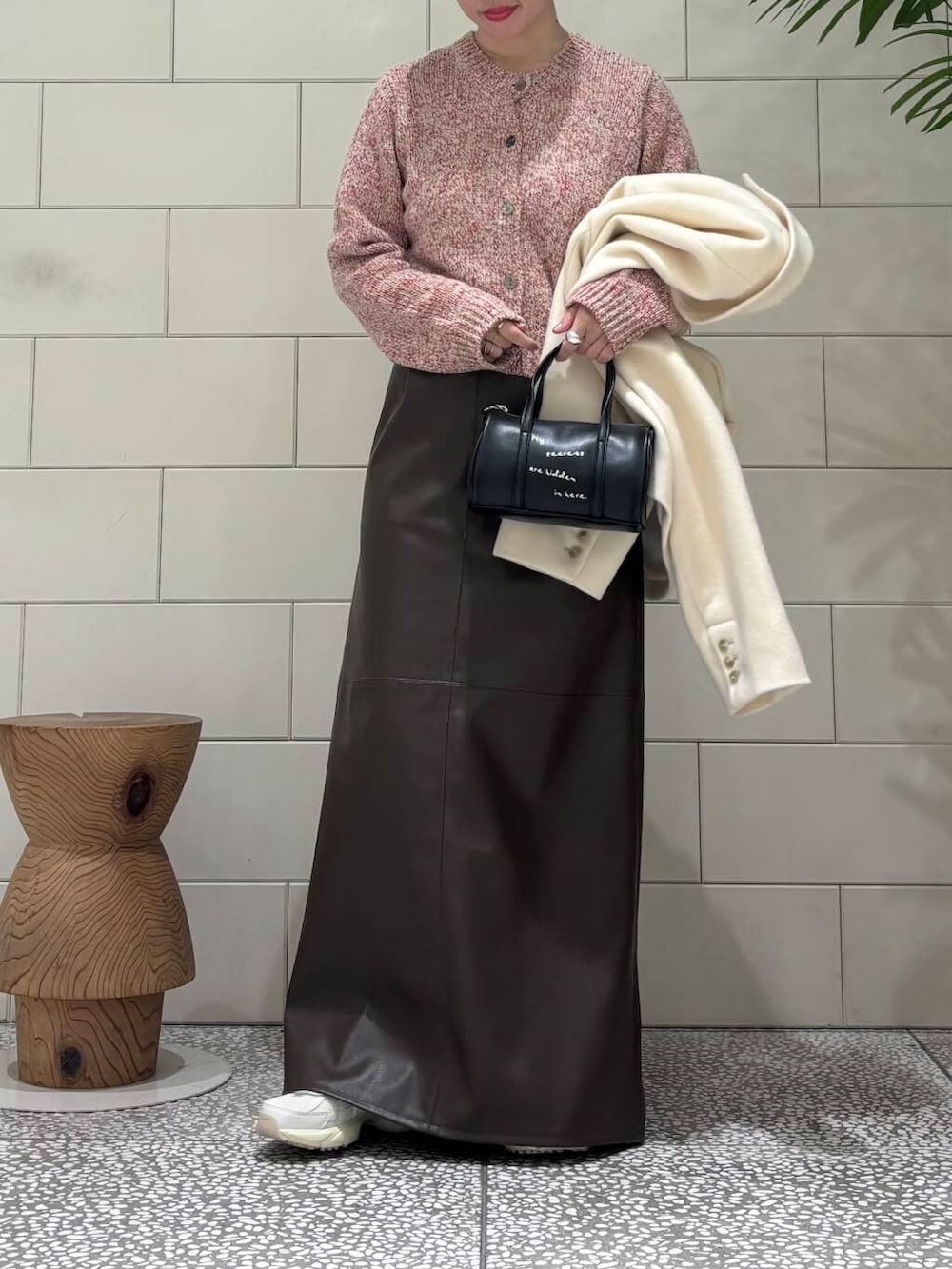 ホワイト系のスニーカー、ブラック系のボストンバッグ、ブラウン系のスカートを着用したレディースの冬コーディネートの2枚目の写真