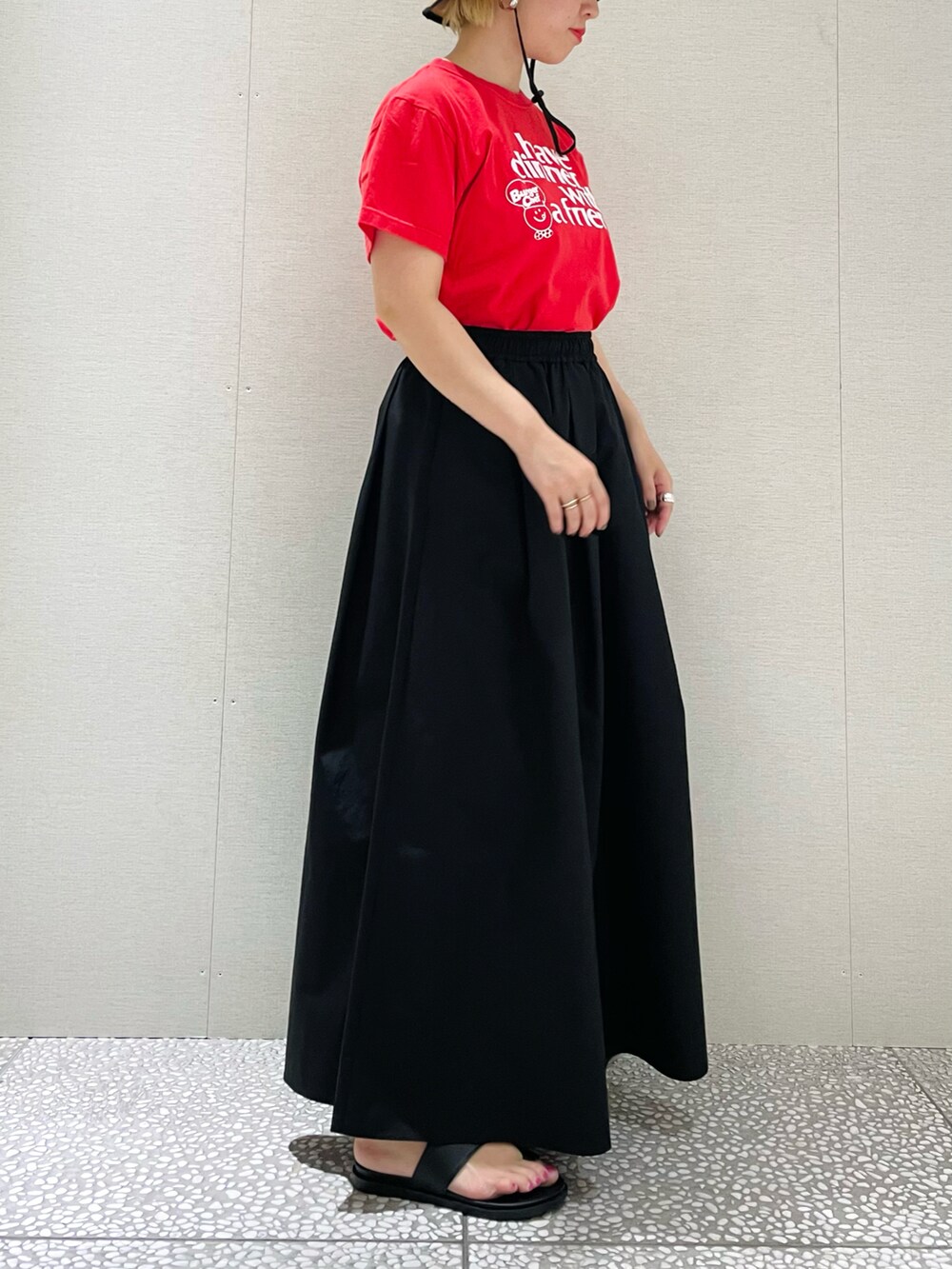 ブラック系のスカート、ブラック系のサンダル、レッド系のTシャツ/カットソーを着用したレディースの春コーディネートの2枚目の写真
