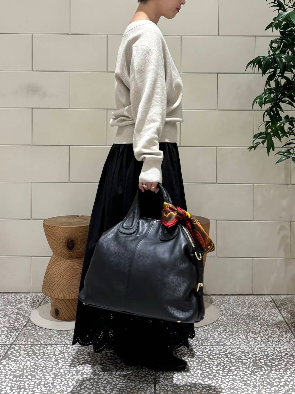 ベージュ系のニット/セーター、ブラック系のボストンバッグ、ブラック系のスカートを着用したレディースの秋コーディネートの2枚目の写真